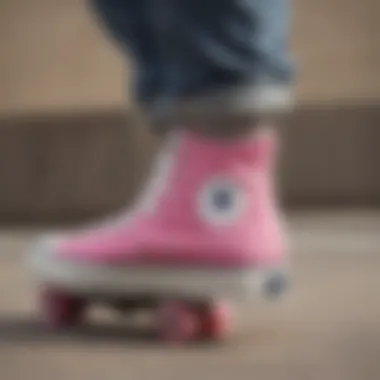 A close-up of a skateboarder wearing pink and white Converse Chuck Taylor shoes while performing a trick.