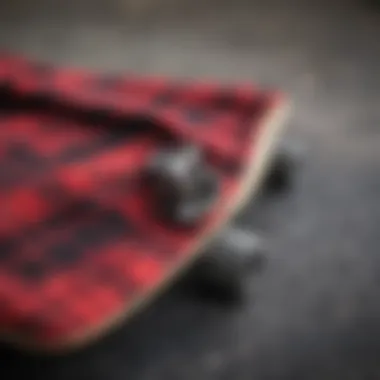 Close-up of a red and black flannel shirt draped over a skateboard.